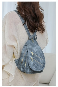 Detalle de bolso de pecho vintage de piel gris con cremalleras doradas y múltiples bolsillos