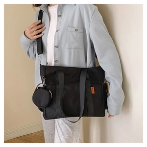 Detail of black nylon tote bag with orange woven label and mini round zipper coin pouch