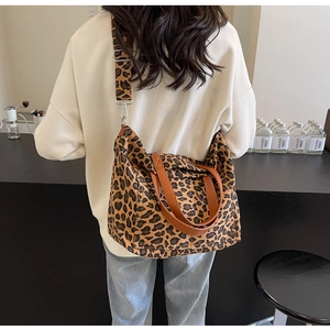 Detail view of leopard print canvas tote bag featuring premium brown leather straps and hardware