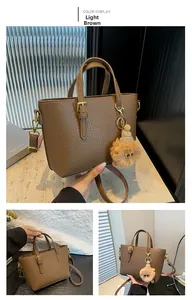 Detail view of light brown leather bucket bag with cute bear charm and golden hardware