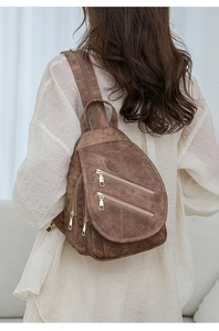 Detalle de bolso de pecho vintage marrón con cremalleras doradas y textura mate suave