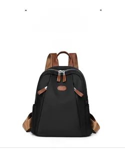 Front view of black nylon backpack with brown leather accents and multi-zipper pockets