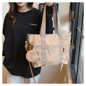 Detail of nylon tote bag featuring wide handles, a round coin purse, and detachable strap