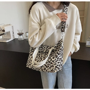 Detail of leopard print canvas tote bag with adjustable wide strap shown on model