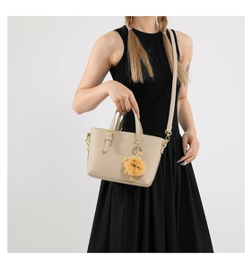 Close-up of beige lychee leather bucket bag with golden hardware and yellow fur charm