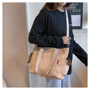 Side view of beige nylon tote bag with functional pockets worn by model
