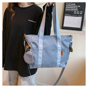 Detail view of light blue nylon tote bag with shoulder strap and mini round pouch charm