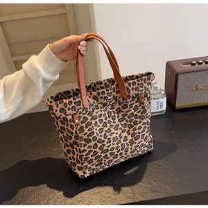 Detail of leopard print tote bag with brown leather handles and side pocket with rivets