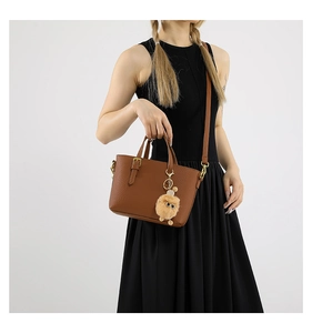 Close-up of brown litchi pattern leather bucket bag with a plush charm and strap