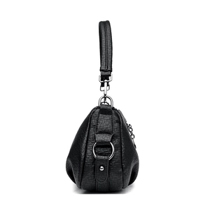 Sac bandoulière élégant en cuir grainé noir avec silhouette incurvée et détails métalliques