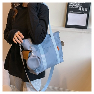 Light blue nylon tote bag worn by model featuring side pocket and round coin pouch