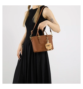 Brown pebbled leather bucket bag featuring a cute plush lion charm and adjustable strap