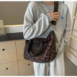 Detail of leopard print tote bag featuring black handles and a matching wide strap