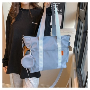 Detail of light blue nylon tote bag featuring a round coin purse and orange label