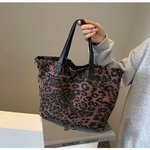 Close-up of large leopard print tote bag with black leather handles and canvas texture