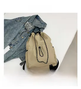 Detail view of beige nylon backpack featuring black and white checkered drawstring closure