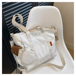 Detailed shot of a white canvas tote bag with side pocket and round coin purse charm
