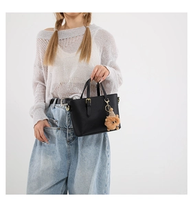 Detail of black pebbled leather bucket bag with gold hardware and lion plush charm