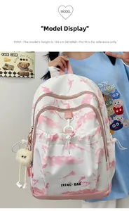 Détail d'un sac à dos blanc avec motif nuages roses, boucles décoratives et pompon doux