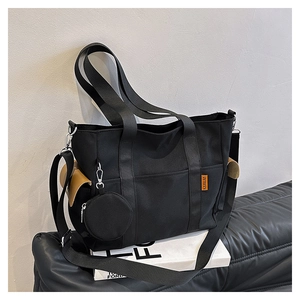 Close-up of black canvas tote bag with nylon strap and detachable round earphone pouch