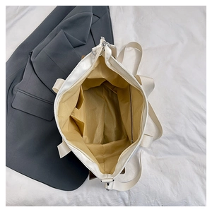 Top view of spacious cream tote bag interior with khaki lining and functional side pockets