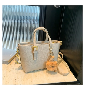 Detailed macro view of beige lychee grain leather texture and gold buckle on bucket bag