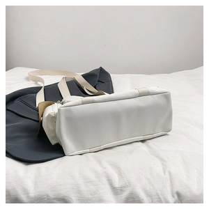 Detail view of reinforced bottom and side zipper on a cream nylon tote bag