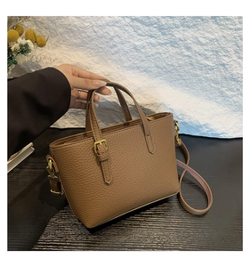 Detail of brown pebbled leather bucket bag with gold hardware and dual handles