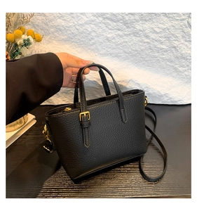 Close-up of black lychee grain leather texture and elegant gold hardware on bucket bag