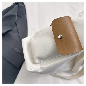Detail of white nylon tote with brown leather flap and silver snap button closure