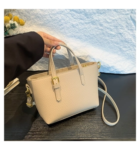 Close-up of cream lychee leather bucket bag with gold hardware and dual handles