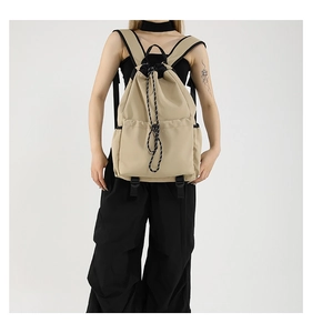Detail of khaki nylon drawstring backpack showing wide straps and side functional pocket