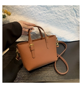 Close-up of brown litchi pattern bucket bag with gold buckle detail and slim shoulder strap