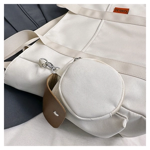 Close-up of cream canvas tote bag with round coin purse and brown leather detail