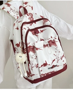 Détail du sac à dos imprimé floral avec motifs de paysages rouges et porte-clés peluche