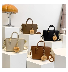 Close-up of pebble leather bucket bags in multiple colors with cute fur pompom charms
