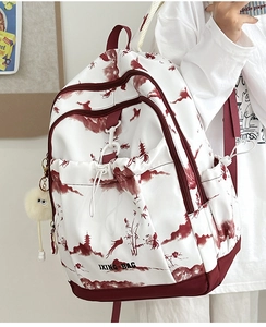 Détail du sac à dos blanc avec imprimé paysage à l'encre et pompon jaune peluche
