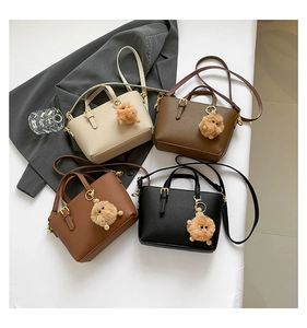 Detail shot of mini bucket bags in four colors with plush ball charms and leather texture