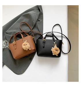 Detail of small textured leather bucket bags in brown and black with cute pompom charms