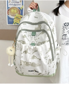 Vue latérale d'un sac à dos floral avec accents vert sauge et pompon en peluche doux