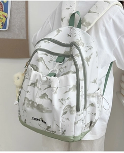 Détail d'un sac à dos imprimé paysage avec sangles vertes et pompon blanc doux