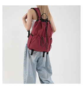 Rear view of model wearing a red nylon drawstring backpack with black adjustable straps