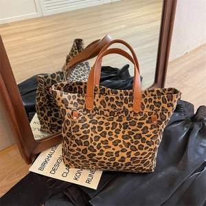 Large leopard print canvas tote bag with brown leather handles shown in a mirror reflection