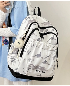 Détail d'un sac à dos blanc avec imprimé peinture à l'encre et pendentif en peluche