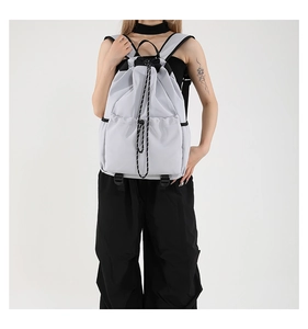 Detailed view of light gray waterproof nylon drawstring backpack worn by a model