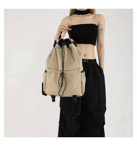 Detail of khaki nylon backpack featuring contrast black drawstring and woven cord closure