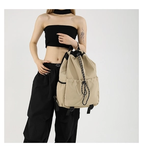 Detail view of khaki nylon drawstring backpack with thick woven cords and side pockets