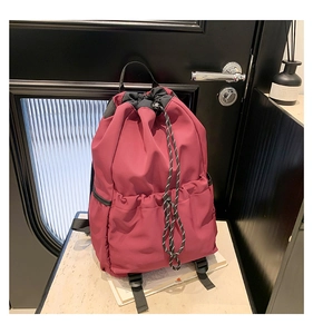 Detailed view of water-resistant burgundy nylon drawstring backpack with side pockets