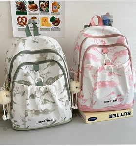 Détail de sacs à dos vert clair et rose avec imprimés paysagers et pendentifs peluche