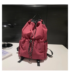 Detail view of red nylon drawstring backpack with front pocket and side storage